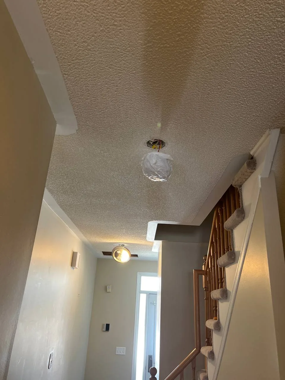 Textured popcorn ceiling in a hallway before removal